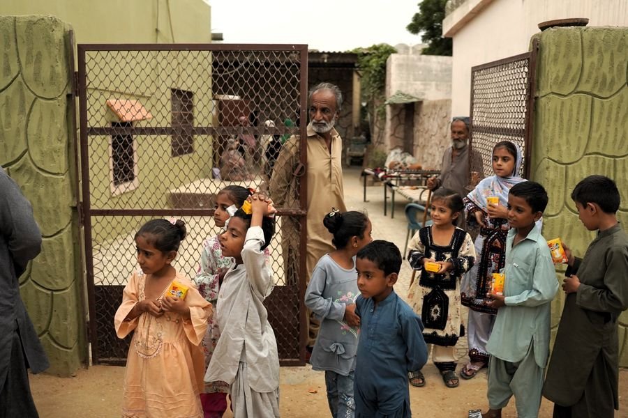 Children in a village in rural Sindh holding juice packs during the relief distribution, August 2026